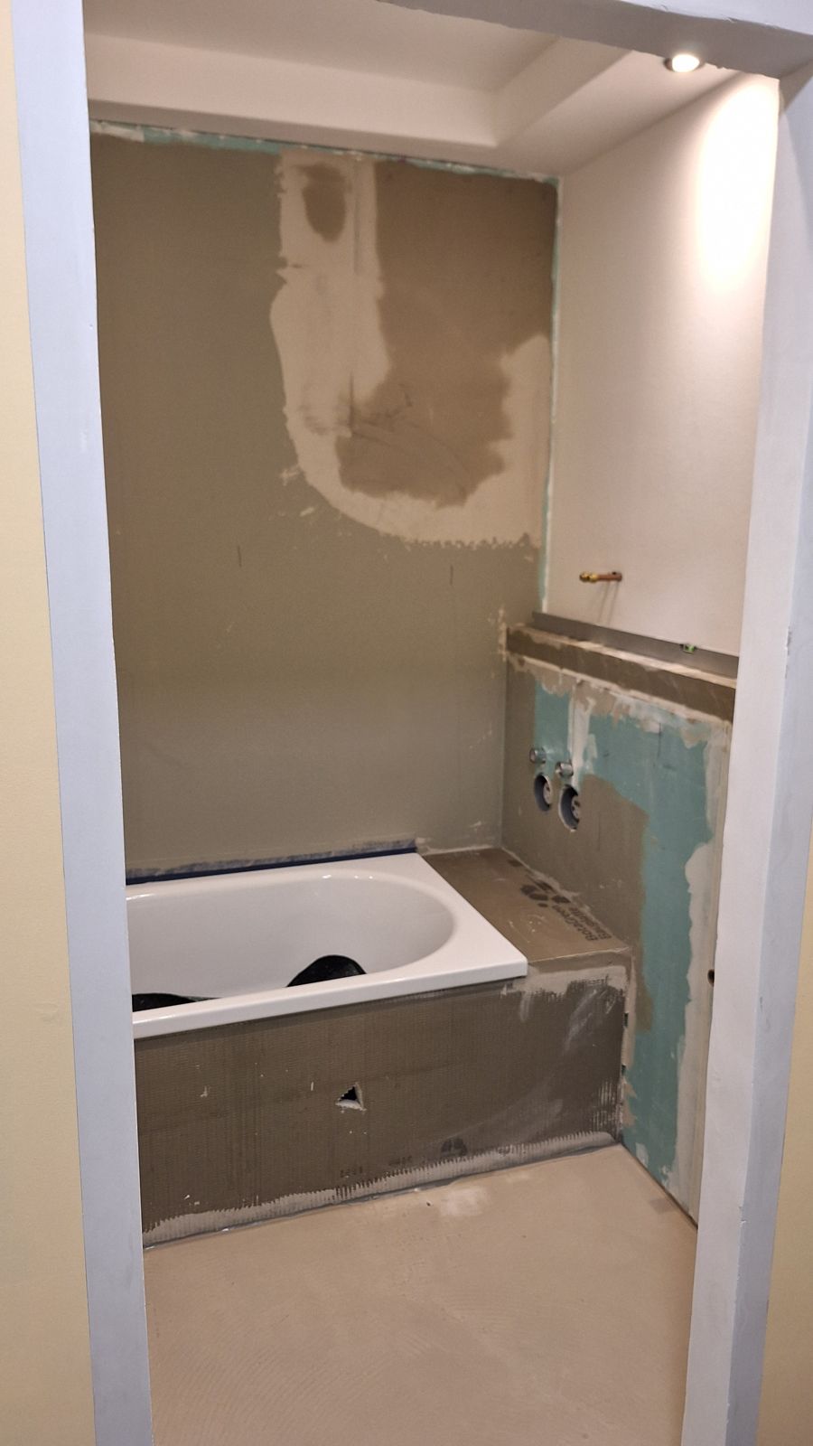 Bad im Rohbau: eingehauste Wanne auf Bauplatten, Vorwand mit imprägnierten Gipsplatten, verputzte Wand, Ausgleichsschicht am Boden